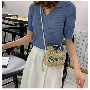 Close-up of straw bucket bag featuring green Summer embroidery and leaf charms