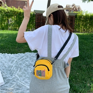 Gros plan sur le sac bandoulière en toile jaune avec illustration de monstre vert