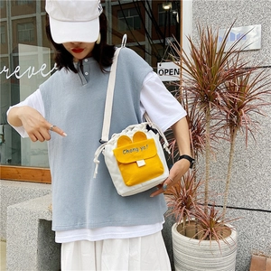 Detail of canvas drawstring bucket bag with yellow contrast pocket and blue slogan