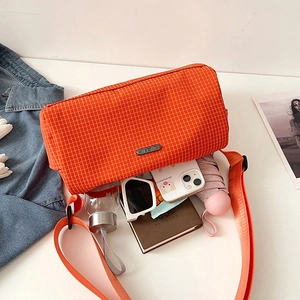 Sac bandoulière en nylon à carreaux orange avec objets du quotidien en vue à 45 degrés