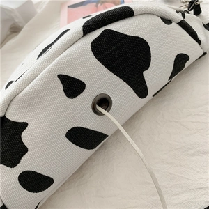 Detail of the headphone jack and white cable on a black and white cow print canvas bag