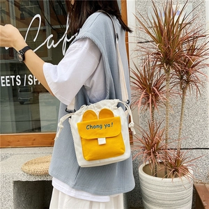 Detail of canvas bucket bag featuring a yellow ear-flap pocket and drawstring closure