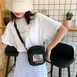 Détail d'un mini sac bandoulière en toile noire avec dinosaure et texte japonais