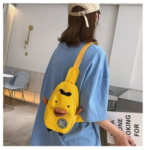 Detail view of a yellow cartoon duck canvas crossbody bag worn by a model in a casual setting