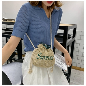 Detailed straw bucket bag featuring green Summer embroidery and a white drawstring rope strap