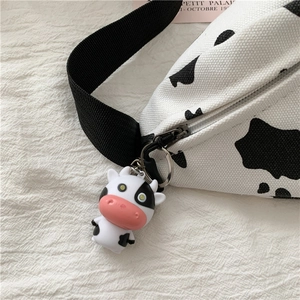 Close-up of cow print canvas chest bag with a 3D cow pendant and black adjustable strap