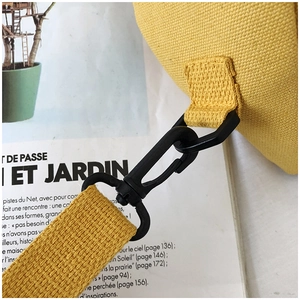 Détail du sac en toile jaune montrant le crochet en plastique et les coutures de renfort