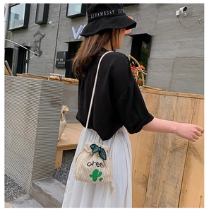 Outdoor street shot of a straw bucket bag with cactus embroidery and drawstring closure
