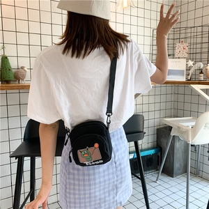 Détail du mini sac bandoulière en toile noire avec motif monstre vert et sangle