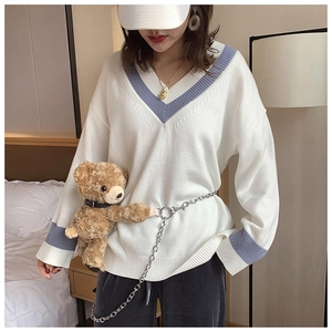 Close-up of V-neck sweater with rib cuffs and a cute bear toy chain belt accessory