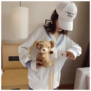 Detail of soft brown plush bear bag with adjustable off-white strap and metallic hardware