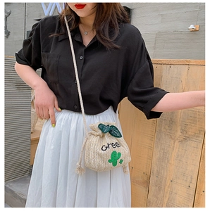Detail of straw bucket bag with green cactus embroidery and cotton drawstring strap