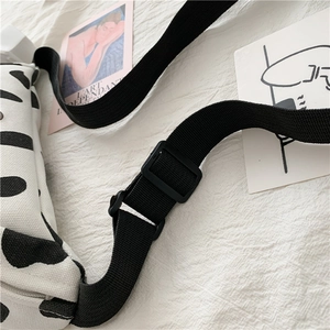Detail of adjustable nylon strap and cow print canvas texture on a stylish crossbody bag