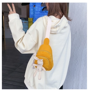 Détail du sac bandoulière en toile jaune avec sangle réglable et breloque lapin en peluche