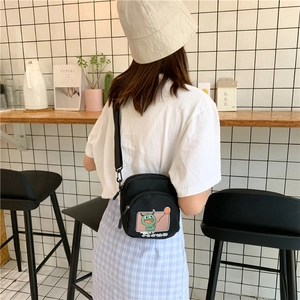 Détail d'un petit sac bandoulière en toile noire avec imprimé monstre vert et fermeture