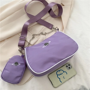 Detail of purple nylon baguette bag featuring planet embroidery and detachable mini pouch