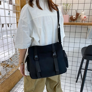 Close-up of black canvas messenger bag featuring adjustable buckles and side zipper pocket