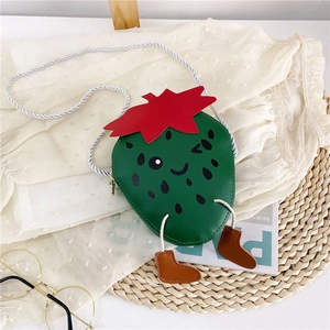 Detail of green strawberry-shaped kids crossbody bag with cartoon face and hanging leg charms