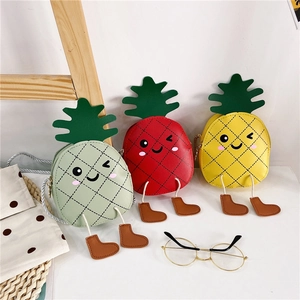 Détail de trois sacs bandoulière en forme d'ananas pour enfants avec visages de dessins animés