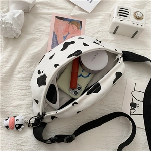 Flat lay of cow print canvas waist bag with interior storage for makeup and phone