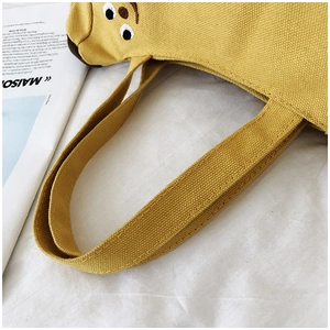 Détail du sac en toile jaune avec coutures soignées et broderie de chien mignon