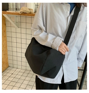 Dettaglio della borsa a tracolla in tela nera minimalista con ampia tracolla e texture