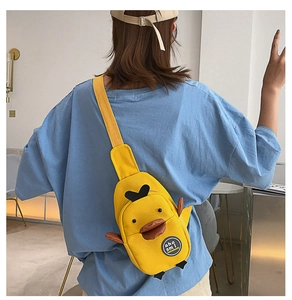 Rear view of a yellow duck canvas crossbody bag worn by a model in a blue t-shirt