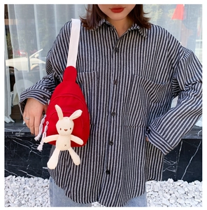 Détail du sac bandoulière en toile rouge avec sangle blanche et breloque lapin mignon