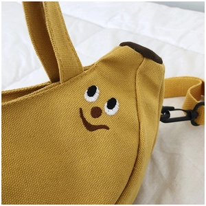 Détail d'un sac bandoulière banane en toile jaune avec visage souriant brodé mignon