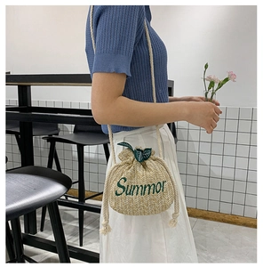 Detail of beige straw bucket bag with green Summor embroidery and drawstring closure