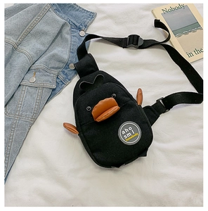 Detail of penguin-shaped canvas crossbody bag showing black fabric and orange leather beak