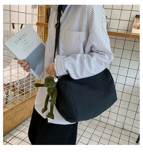 Dettaglio della borsa a tracolla in tela nera con ciondolo a forma di rana di peluche
