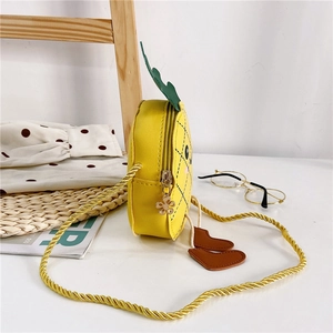 Détail du sac à bandoulière enfant en forme d'ananas jaune avec pieds et pendentif fleur