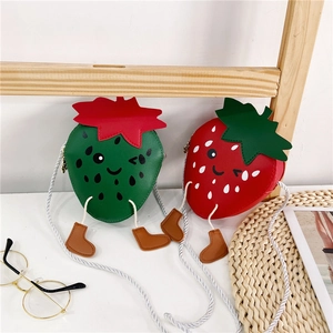 Detail of cute strawberry cartoon crossbody bags for girls in red and green colors