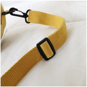 Détail de la bandoulière réglable en toile jaune vif avec boucle noire et mousqueton