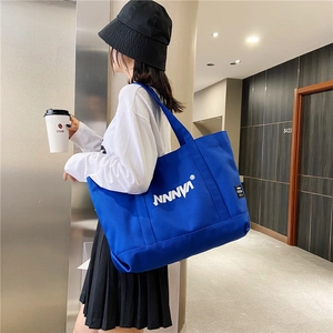 Detail of royal blue canvas tote bag showing wide shoulder strap and artistic text