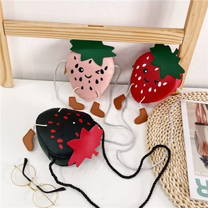 Detailed view of cute strawberry-shaped kids cross-body bags in pink, red, and black