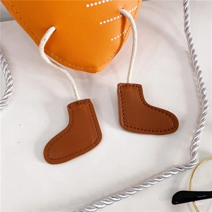 Détail d'un sac à bandoulière orange pour enfants avec un design créatif de jambes de poupée