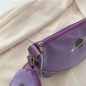 Detail of purple nylon baguette bag featuring planet embroidery and silver chain decor