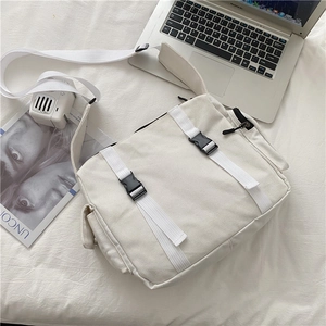 Detail view of large canvas crossbody bag featuring dual buckle closures and side pocket
