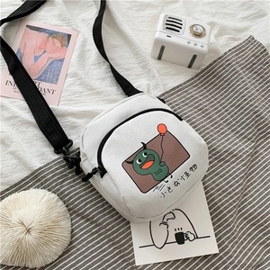 Détail du sac bandoulière en toile blanche avec monstre de dessin animé et sangle noire