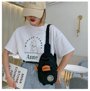 Detail of a black canvas duck chest bag with orange 3D beak on a white t-shirt
