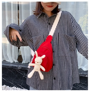 Détail du sac bandoulière en toile rouge avec un lapin tricoté et une large sangle crème