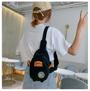 Detail of cute black duck-shaped canvas chest bag with 3D orange beak and wings