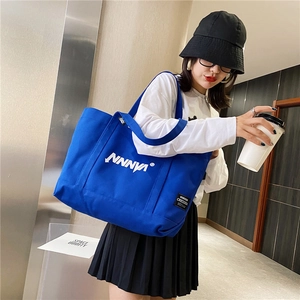 Close-up of a blue canvas tote bag with white lettering and brand label detail
