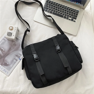 Detail of black canvas messenger bag featuring plastic buckles and wide shoulder strap