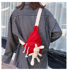 Détail du sac bandoulière en toile rouge avec un lapin en peluche et sangle réglable