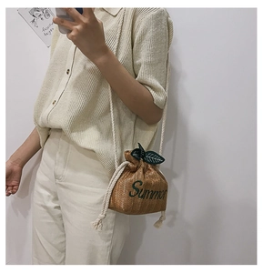 Detail of straw bucket bag featuring green Summer embroidery and leaf ornament