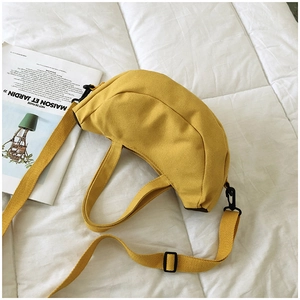 Détail du sac bandoulière demi-lune en toile jaune avec sangles réglables sur le lit