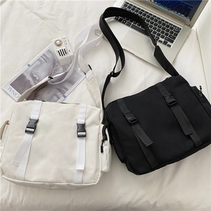 Detailed top view of large canvas messenger bags in black and beige with buckle closures